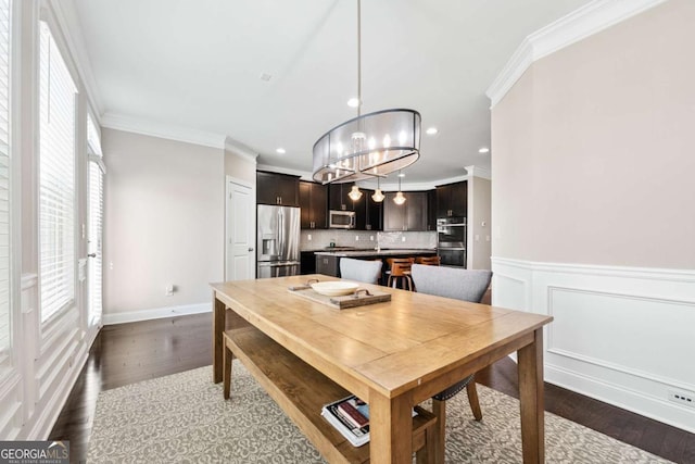 dining room with dark wood-style floors, wainscoting, recessed lighting, and crown molding