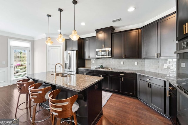 kitchen featuring visible vents, appliances with stainless steel finishes, light stone countertops, crown molding, and a sink