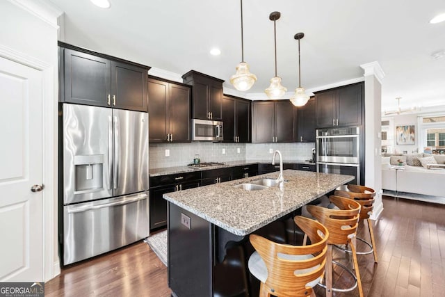 kitchen featuring light stone counters, appliances with stainless steel finishes, backsplash, and a sink