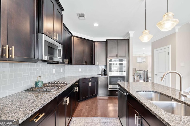 kitchen with tasteful backsplash, visible vents, light stone counters, stainless steel appliances, and a sink