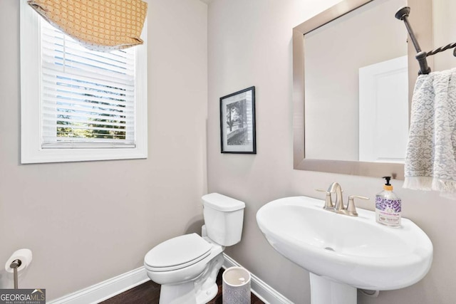 bathroom with wood finished floors, a sink, toilet, and baseboards