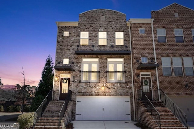 view of property featuring driveway, a garage, and brick siding