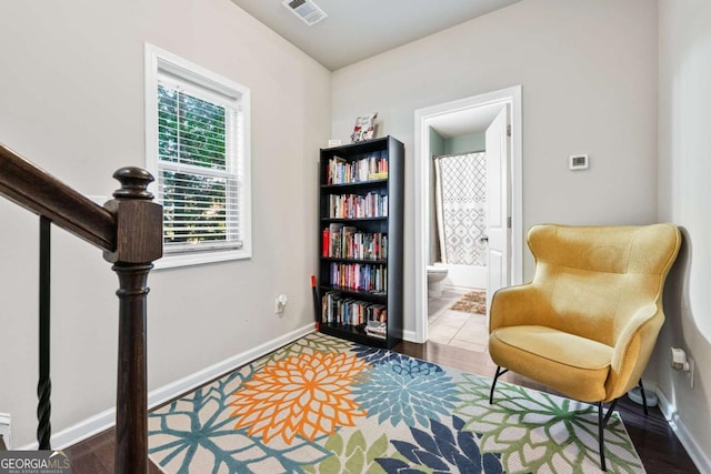 living area featuring baseboards, visible vents, and wood finished floors