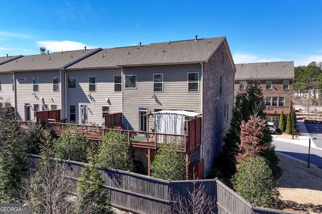 back of house featuring brick siding and fence