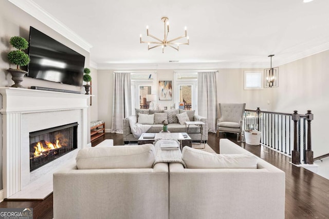 living area with crown molding, dark wood-type flooring, a high end fireplace, and a notable chandelier