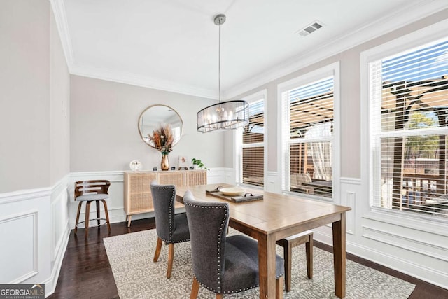 dining room with a wainscoted wall, visible vents, ornamental molding, dark wood finished floors, and an inviting chandelier