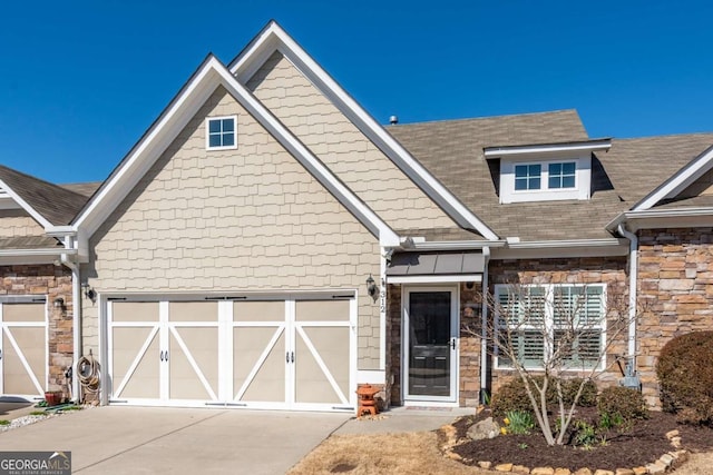 view of front of property featuring a garage, stone siding, and concrete driveway