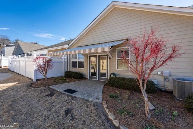 entrance to property with a patio, french doors, fence, and central air condition unit