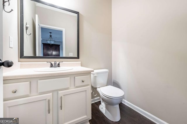 bathroom with toilet, baseboards, wood finished floors, and vanity