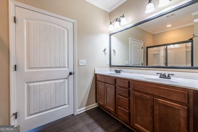 bathroom with wood finished floors, a sink, visible vents, double vanity, and crown molding