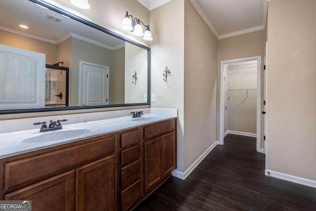 bathroom with crown molding, visible vents, a sink, and wood finished floors