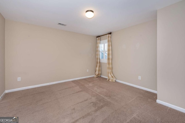 empty room with carpet floors, visible vents, and baseboards