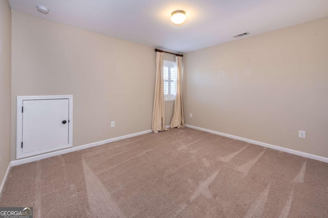 empty room with carpet floors, visible vents, and baseboards