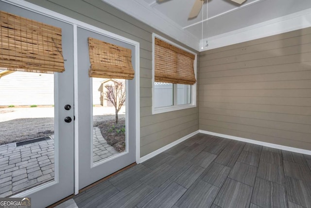 doorway to outside with baseboards, a ceiling fan, and wooden walls