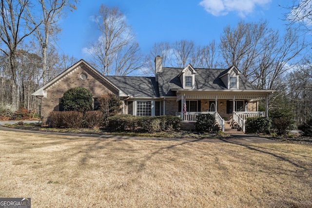 cape cod-style house with brick siding, a front lawn, and a porch