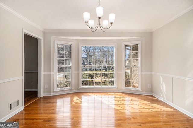 unfurnished dining area featuring a notable chandelier, light wood finished floors, visible vents, ornamental molding, and baseboards