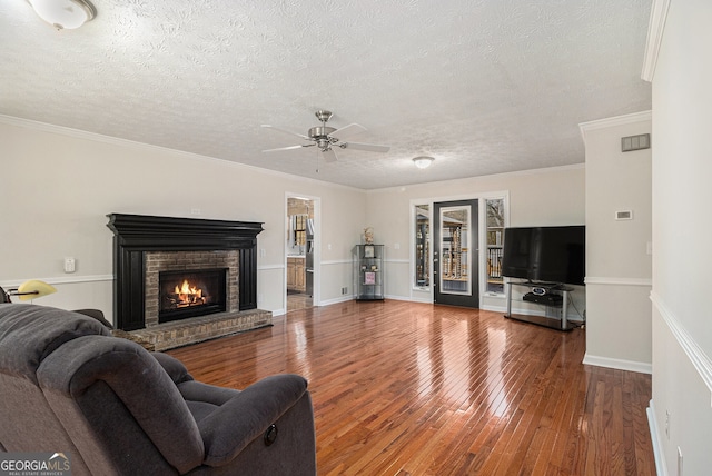 living room with hardwood / wood-style flooring, a fireplace, crown molding, and a textured ceiling