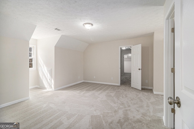 bonus room with light carpet, a textured ceiling, visible vents, and baseboards