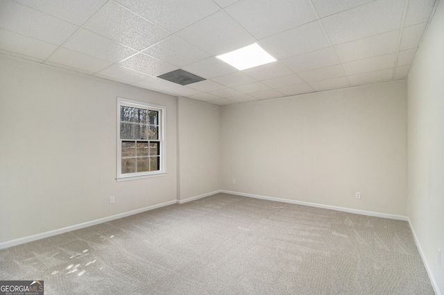 unfurnished room featuring carpet, a drop ceiling, and baseboards