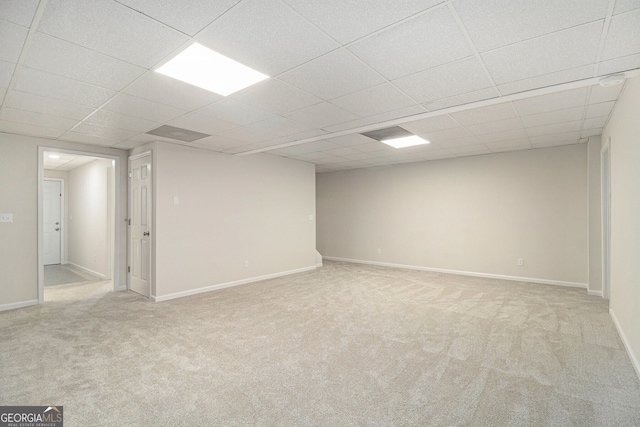 finished basement with carpet floors, a drop ceiling, and baseboards