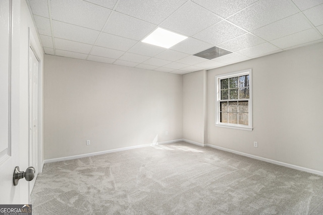 empty room featuring carpet floors, baseboards, and a paneled ceiling