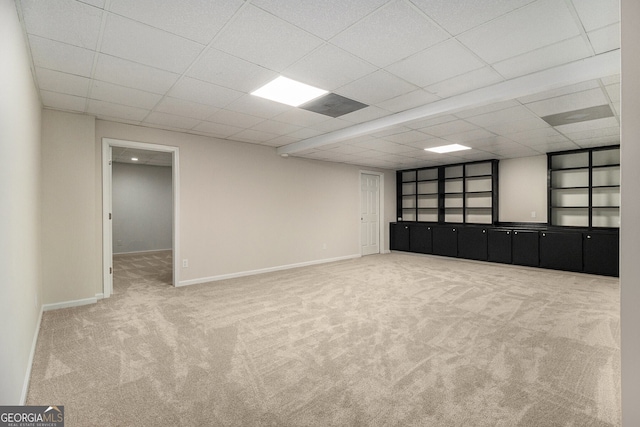 empty room featuring a paneled ceiling, carpet, and baseboards