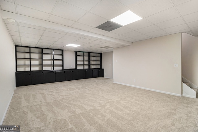 finished basement with a paneled ceiling, carpet flooring, built in features, baseboards, and stairway