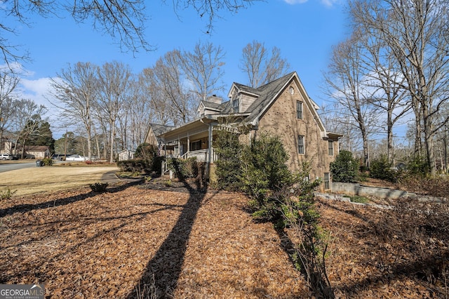 view of side of home with a porch and a chimney