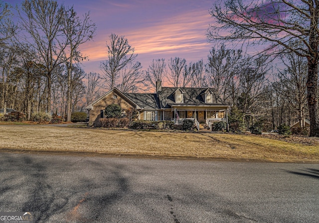 new england style home with covered porch and a front lawn