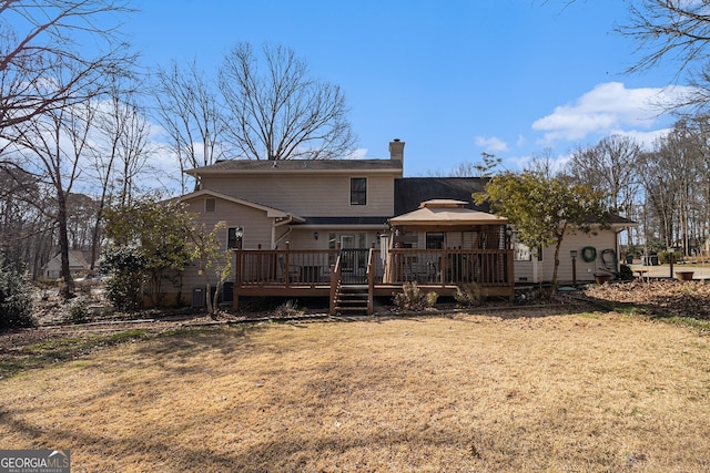 rear view of property with a deck, a chimney, and a lawn