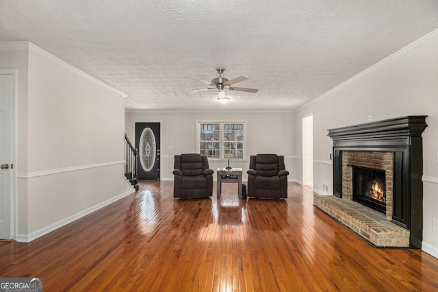 sitting room with hardwood / wood-style flooring, stairway, crown molding, a textured ceiling, and a fireplace