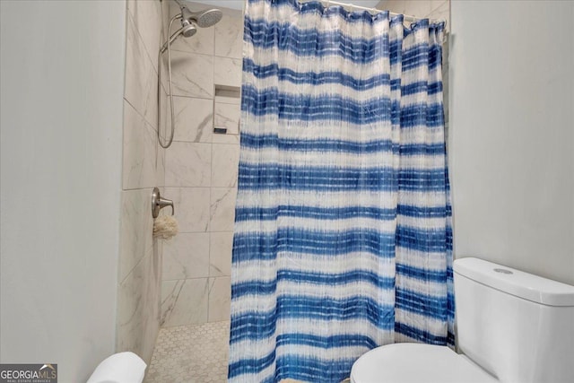 bathroom with a tile shower and toilet