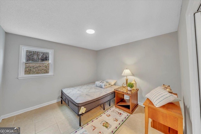 bedroom featuring light tile patterned floors, a textured ceiling, and baseboards