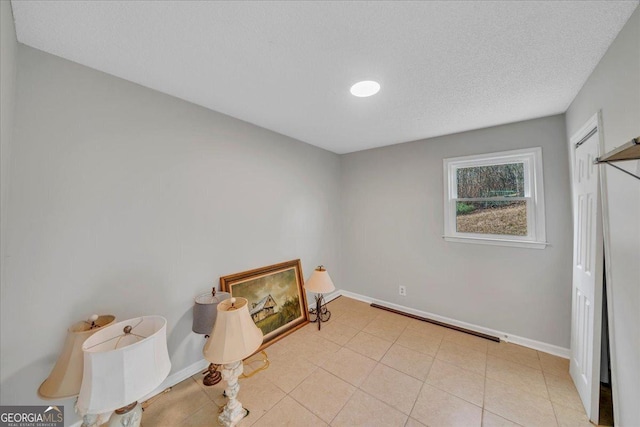 interior space with baseboards, a textured ceiling, and tile patterned floors