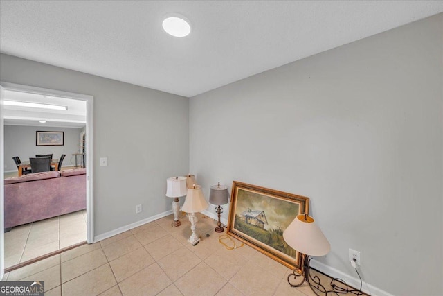 sitting room featuring light tile patterned flooring, a textured ceiling, and baseboards