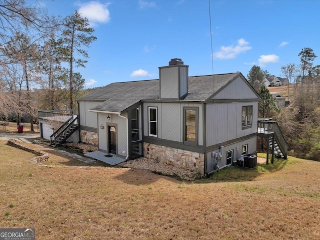 back of property featuring stone siding, stairway, cooling unit, and a lawn