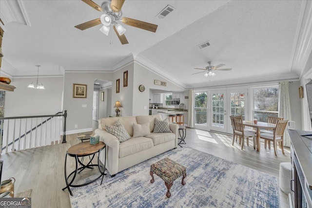 living room with a textured ceiling, light wood-type flooring, and visible vents