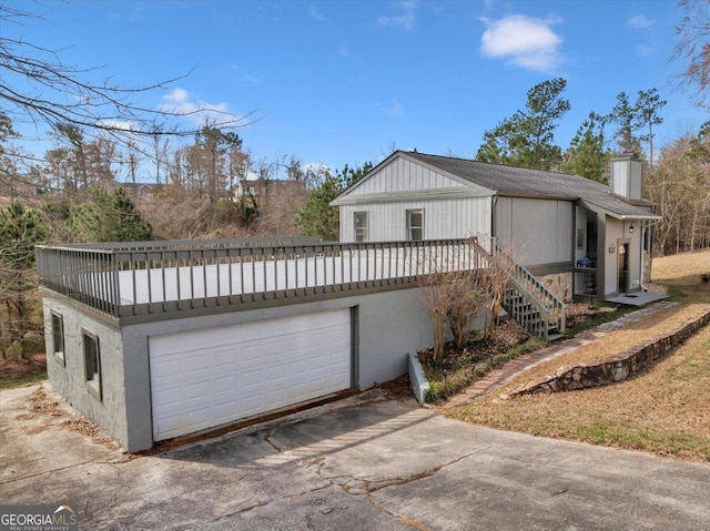 view of front of house featuring a garage, driveway, a chimney, and stairs