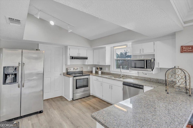 kitchen featuring under cabinet range hood, a peninsula, a sink, visible vents, and appliances with stainless steel finishes