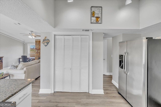 kitchen featuring light wood-style floors, stainless steel fridge, visible vents, and light stone countertops