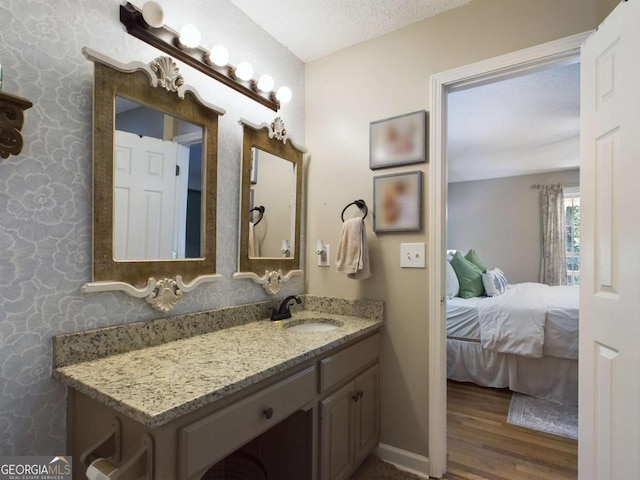 bathroom with baseboards, wood finished floors, ensuite bathroom, a textured ceiling, and vanity