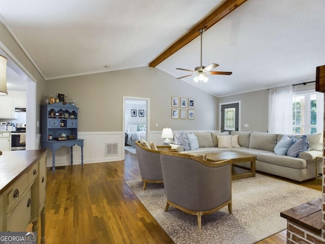 living area with visible vents, lofted ceiling with beams, a wainscoted wall, ornamental molding, and dark wood-style flooring