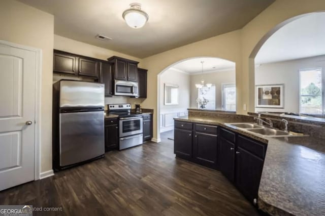 kitchen featuring visible vents, arched walkways, appliances with stainless steel finishes, dark wood-type flooring, and a sink