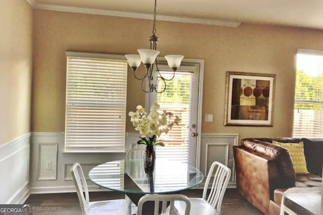 dining space with a wainscoted wall, a decorative wall, ornamental molding, and an inviting chandelier