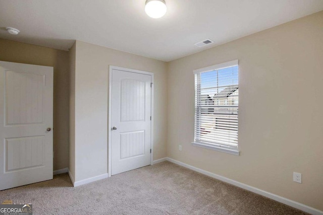 unfurnished bedroom with carpet floors, visible vents, baseboards, and a closet