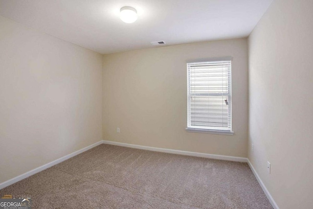 empty room featuring baseboards, visible vents, and carpet flooring