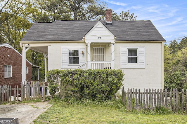 bungalow-style house with fence, a chimney, a front lawn, a shingled roof, and concrete block siding