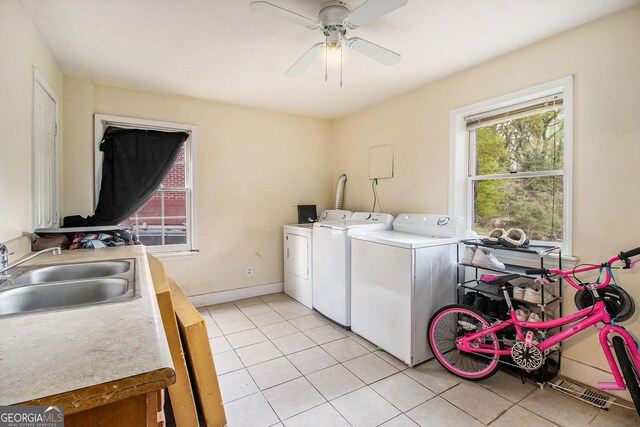 laundry area with light tile patterned flooring, ceiling fan, laundry area, a sink, and washing machine and dryer