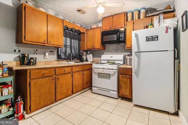 kitchen featuring light countertops, a sink, a textured ceiling, white appliances, and visible vents