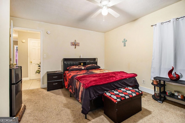 bedroom featuring freestanding refrigerator, baseboards, light colored carpet, and ceiling fan